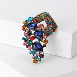 Close-up of vintage bronze brooch with blue pear-shaped gems and colorful crystals