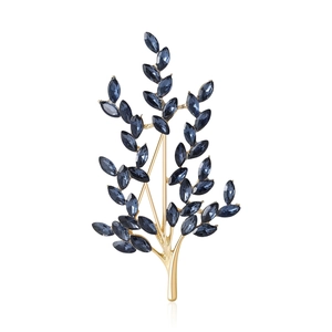 Elegant gold leaf brooch with navy blue marquise crystals on a white background