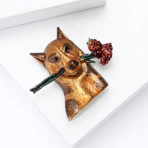 Detail shot of a bronze dog brooch holding a red flower on a white geometric stage