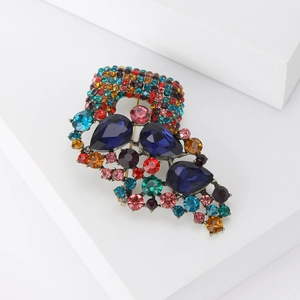 Detailed macro shot of vintage alloy brooch with colorful rhinestones and blue pear gems