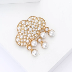 Détail macro d'une broche nuage en alliage avec perles et effet gouttes sur support blanc
