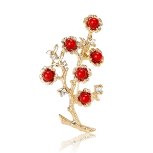 Vintage golden branch brooch with red beads and white rhinestones on white background