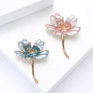 Spille a fiore eleganti in smalto rosa e blu con steli dorati su sfondo bianco