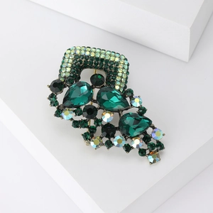Detail of vintage emerald green rhinestone brooch with antique gold metal finish