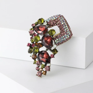 Macro detail of vintage alloy brooch with red pear-cut crystals and colorful rhinestones