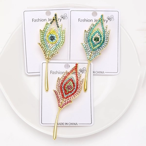 Dettaglio di spille a piuma di pavone con strass colorati su un piatto di ceramica