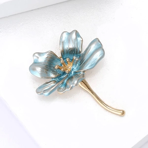 Dettaglio ravvicinato di una spilla a fiore in smalto blu con petali dorati su base