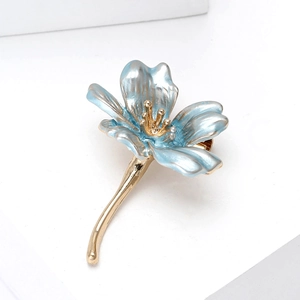 Dettaglio macro di una spilla a fiore dorato con eleganti petali in smalto celeste