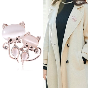 Broche en or rose avec pierres oeil de chat roses et cristaux brillants sur manteau beige