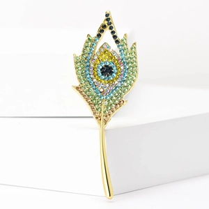 Dettaglio della spilla vintage a piuma di pavone con strass colorati e finitura dorata