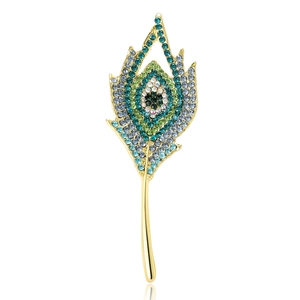 Spilla vintage a piuma di pavone dorata con strass verdi e blu su sfondo bianco