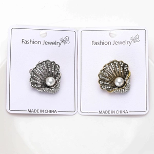 Dettaglio delle spille a conchiglia retrò con strass e perle su cartoncini bianchi