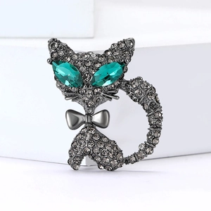Broche chat élégante avec yeux en cristal émeraude et strass gris sur fond pierre