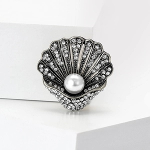 Dettaglio di spilla a conchiglia vintage argento con strass e grande perla bianca
