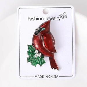Detail of red cardinal brooch with green holly leaves and white rhinestone accents