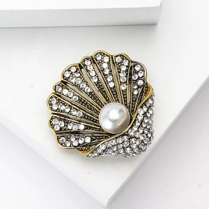 Spilla a conchiglia vintage con perle e strass su sfondo geometrico bianco