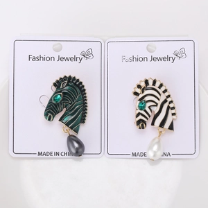 Détail de la broche zèbre en émail avec perle pendante et yeux en pierre verte