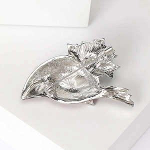 Silver enamel bird brooch featuring a secure safety pin closure on textured metal back