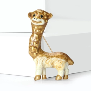 Dettagli di una simpatica spilla a forma di alpaca con bordi dorati e smalto bianco