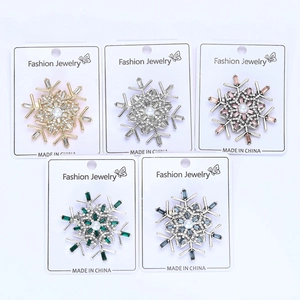 Detail of five snowflake brooches with colorful rhinestones and white pearls on white base
