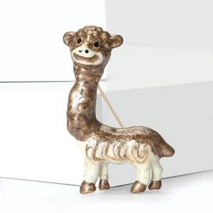 Dettaglio macro di una spilla a forma di alpaca in smalto con finitura in bronzo