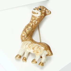 Dettaglio della spilla a forma di alpaca con base in metallo dorato e smalto bianco
