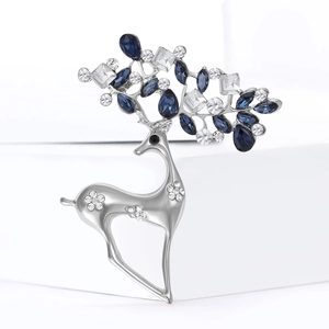 Elegante spilla a renna argentata con strass blu e trasparenti su espositore bianco