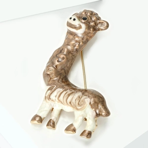 Dettaglio della spilla a forma di alpaca con texture sabbia dorata e smalto bianco