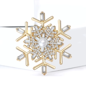 Detailed view of a golden snowflake brooch with a central pearl and sparkling rhinestones