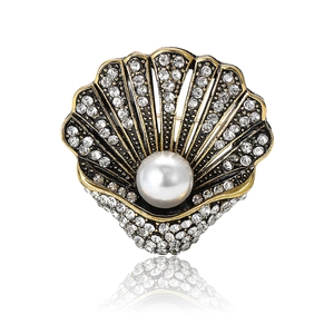 Spilla a conchiglia vintage con strass scintillanti e grande perla su sfondo bianco