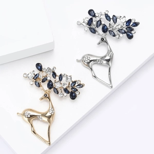 Spille a forma di renna in oro e argento con strass blu su un blocco espositivo bianco