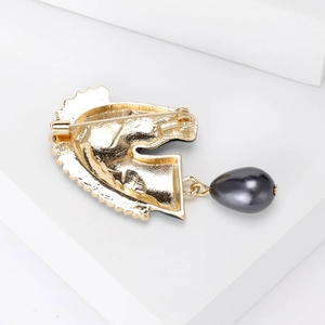 Broche tête de zèbre dorée avec perle grise foncée sur fond blanc épuré