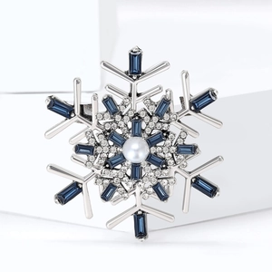 Detailed close-up of a snowflake brooch with blue gems and a white pearl accent