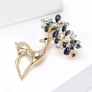 Spilla renna dorata con cristalli blu e strass su un supporto bianco elegante