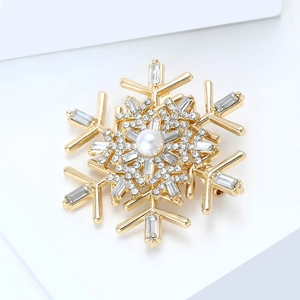 Close-up of golden snowflake brooch with white pearl and sparkling crystals
