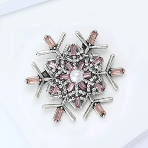 Detail view of snowflake brooch with pink crystals, white pearl, and silver metal finish