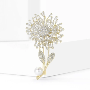 Elegant gold dandelion brooch with baguette cubic zirconia and pearl on a white pedestal
