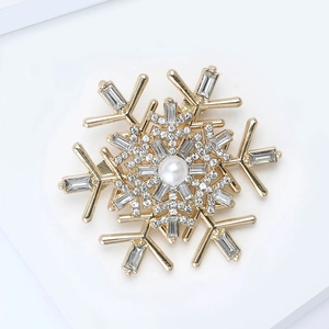 Macro view of snowflake brooch with gold plating, central pearl and crystal details