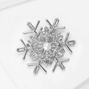 Detail of silver snowflake brooch with baguette zirconia stones and central white pearl