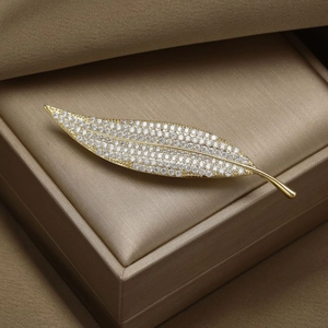 Elegant gold leaf brooch with micro-paved zircons in a brown satin gift jewelry box