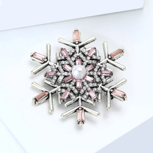 Macro shot of silver snowflake brooch with pink rhinestones and a white faux pearl center