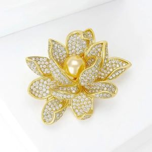 Détail d'une broche lotus dorée avec micro-zirconiums et une grande perle dorée centrale