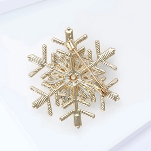 Detailed back view of gold snowflake brooch showing safety pin clasp and metal texture