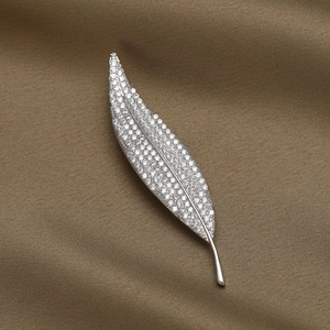 Close-up of silver leaf brooch with micro-pave zircons on luxury brown silk fabric
