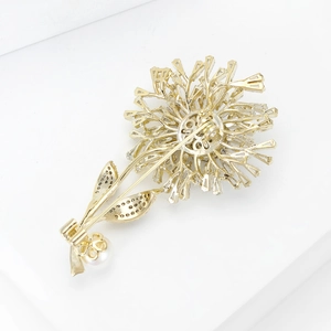 Detailed close-up of a gold dandelion brooch with sparkling zircon and a white pearl