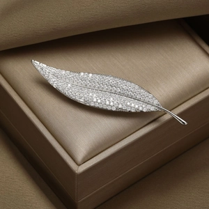 Elegant leaf-shaped brooch with shimmering zircons on silver polished base