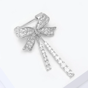Dettaglio elegante spilla a fiocco in argento con pavé di zirconi e nappe a catena