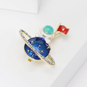 Spilla creativa con astronauta e pianeta blu con strass scintillanti e bandiera a cuore d'oro