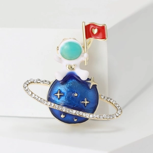 Dettaglio della spilla astronauta con pianeta blu, anello d'oro e bandiera cuore rossa