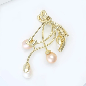 Detail of elegant gold brooch featuring a bow design and three hanging freshwater pearls